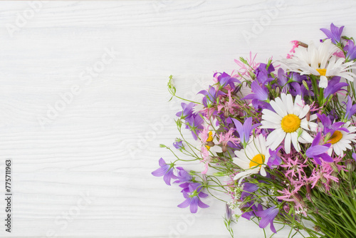 A bouquet of wildflowers lie on a white wooden surface