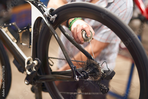 Close up of repairman is lubricate the bike chain in workshop. High quality photo