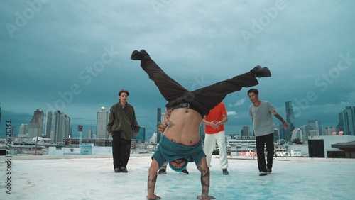 Hispanic hipster dancing surrounded by multicultural friend at city view with blue sky. Group of street dancer performing at rooftop. Active, fun, happy atmosphere. Outdoor sport 2024. Endeavor.
