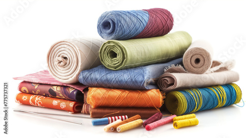 Stack of colorful fabric rolls with threads and needles on white. photo