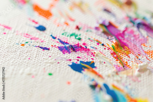 A close-up photo of a colorful paint splatter on a white canvas © Veniamin Kraskov