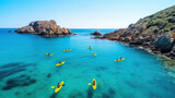Aerial view of yellow kayaks in blue sea in summer. Man on floating canoe in clear azure water, rocks, stones. Active travel. Top view