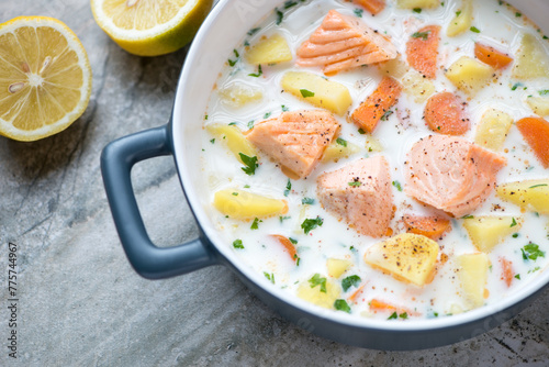 Grey serving pan with lohikeitto or finnish salmon soup, horizontal shot, middle closeup, selective focus