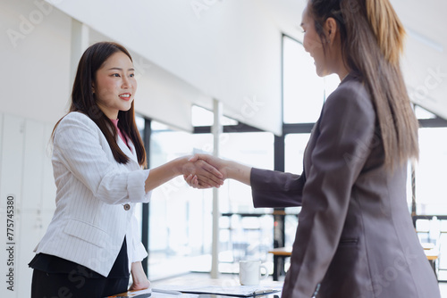 Businesswoman partnership handshake concept. Two young asian business professionals celebrating teamwork in an office, Colleague in meeting.