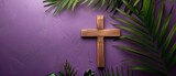 A religious cross and palm leaves are on a purple background. It is a Good Friday, Lent Season, and Holy Week concept.