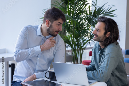 Fotografía deux collègues, jeunes employés de bureau travaillent en équipe et discutent ass