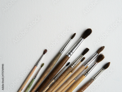 wooden watercolor brushes lie on a white canvas