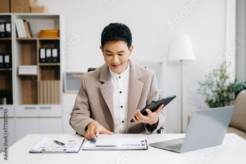 Photography Asian businessman are delighted and happy with the work they do on their tablet, laptop and taking notes at the office
