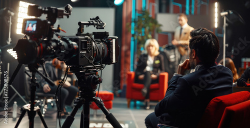 Behind scenes of television interview set: professional cameras aimed at guest speaker with host, highlighting media production and broadcast journalism.