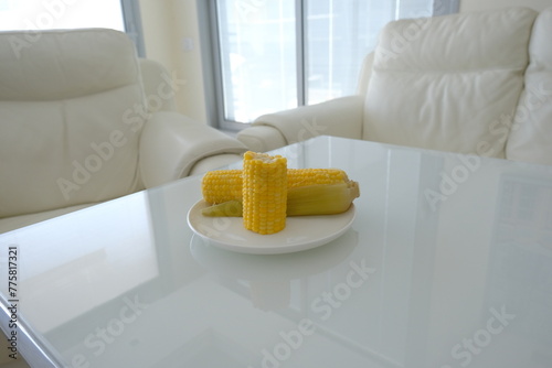 yellow corn on a white plate. boiled yellow corn on white plate and white table