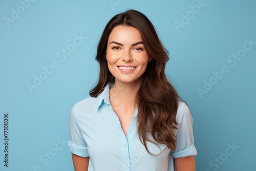 A woman with long brown hair is smiling and wearing a blue shirt