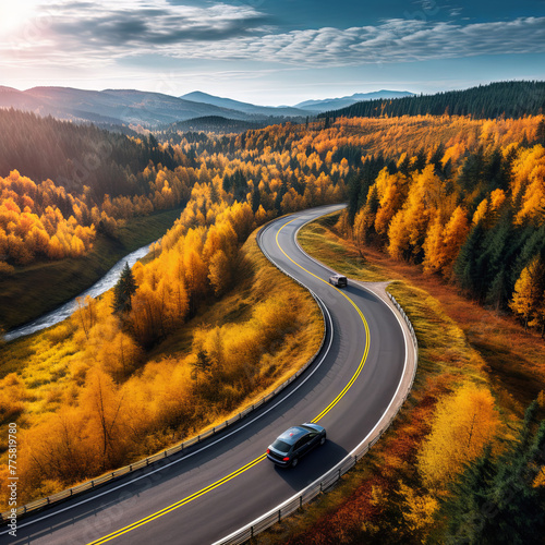 Top view of a car driving on a highway among mountains and autumn colorful forest. Car travel concept