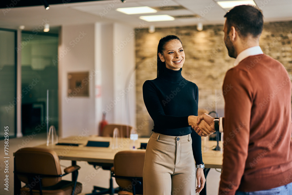 Businesswoman and businessman shaking hands at the office, smiling. Businesswoman and businessman shaking hands at the office, smiling.