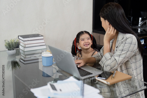 Business woman working at home. working woman working on laptop and take care of her daughter during summer © itchaznong