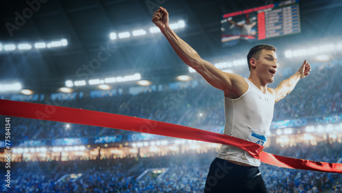Professional Runner Competing In National Championship. A strong Caucasian Male Athlete is Sprinting Towards the Line in a Crowded Stadium, Crossing the Race Finish with His Hands in the Air photo
