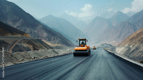 A road roller smoothly paved a freshly constructed asphalt road, with mountainous scenery in the background photo