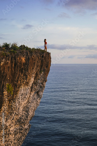 Young Woman Standing On The Edge Of The Cliff Watching At The Ocean In Bali  Indonesia