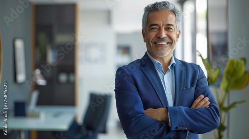 Winner mid aged business man ceo standing in office arms crossed. Smiling mature confident professional executive manager, proud lawyer, confident businessman leader wearing blue suit, portrait. 