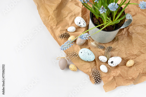 Easter eggs and light blue muscari flowers in cup on a white table. Easter still life. Top view