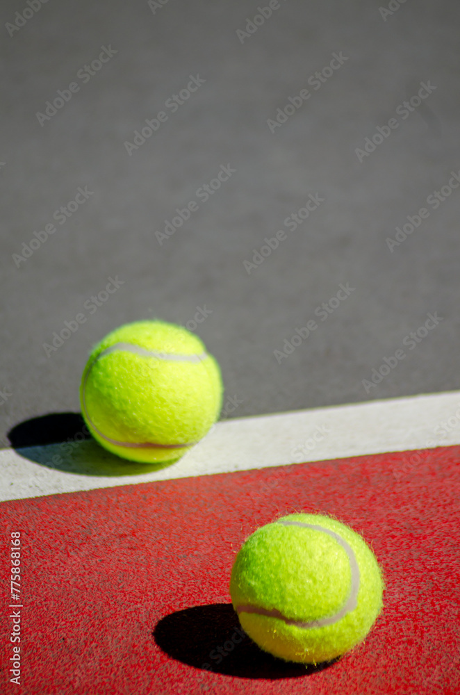 two tennis balls on a red and gray court, racket sports concept