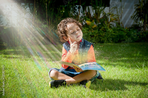 Criança sentada no gramado lendo um livro, pensativo com raios de sol ao fundo, cenário ludico infantil
