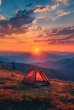 A tent pitched up on a grassy hill at sunset. Perfect for outdoor and adventure themes