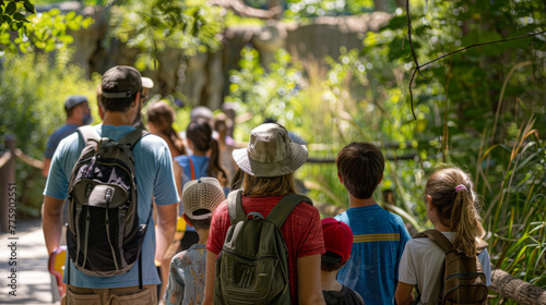 A group of visitors of various ages on a zoo pathway, engaged in wildlife observation and education