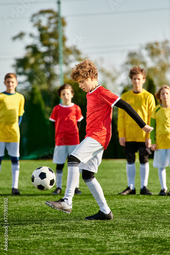 A young boy energetically kicks a soccer ball across a sprawling green field. The bright sun casts long shadows as he skillfully maneuvers the ball, showing determination and passion for the sport.