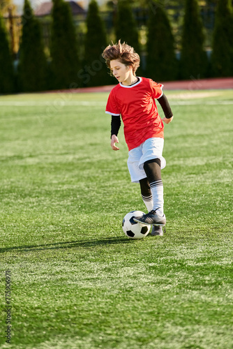 A young boy is seen confidently kicking a soccer ball on a vibrant field. He is focused and determined, displaying skill and passion for the sport. © LIGHTFIELD STUDIOS