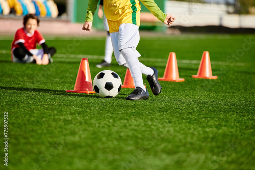 A determined young boy practices dribbling a soccer ball around cones on a sports field, showcasing his agility and precision in each kick. 