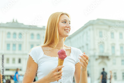 A young white woman eats ice cream and is happy during summer
