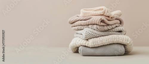 Pile of baby jersey sweaters and textile in beige pastel, with empty copy space