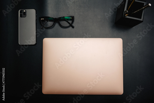 Business layout with items for design. Phone, glasses, pen, laptop on the table. In a dark style, there are object layouts on the table. Top view of items
