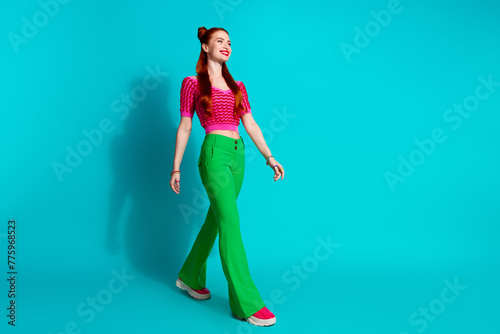 Full length photo of funky adorable lady dressed pink knitted shirt walking emtpy space isolated blue color background © deagreez