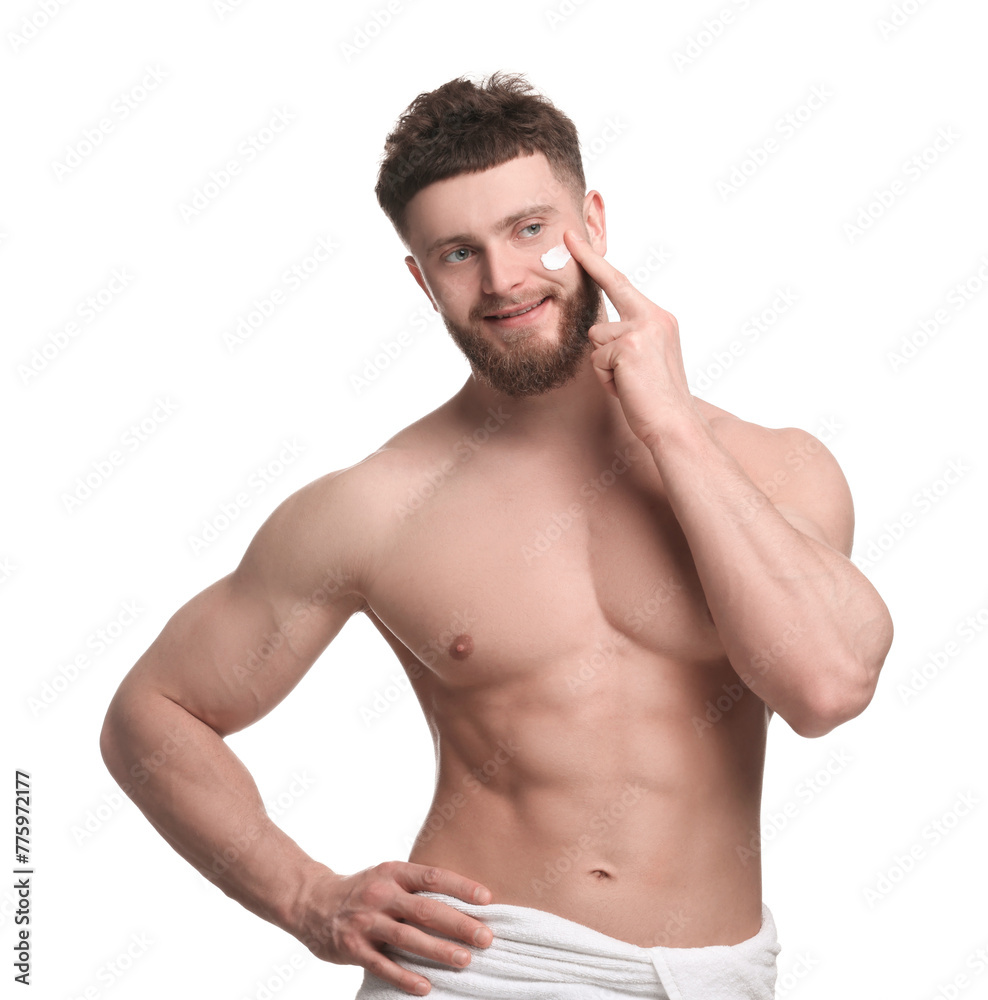 Fototapeta premium Handsome man applying moisturizing cream onto his face on white background