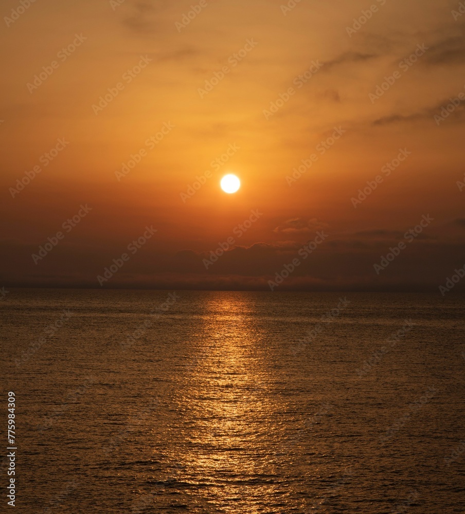 Vertical shot of a vibrant sunset over a tranquil sea on the darkening evening