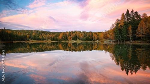 Beautiful scenery of fall trees around Felixer lake with reflection in water at sunset