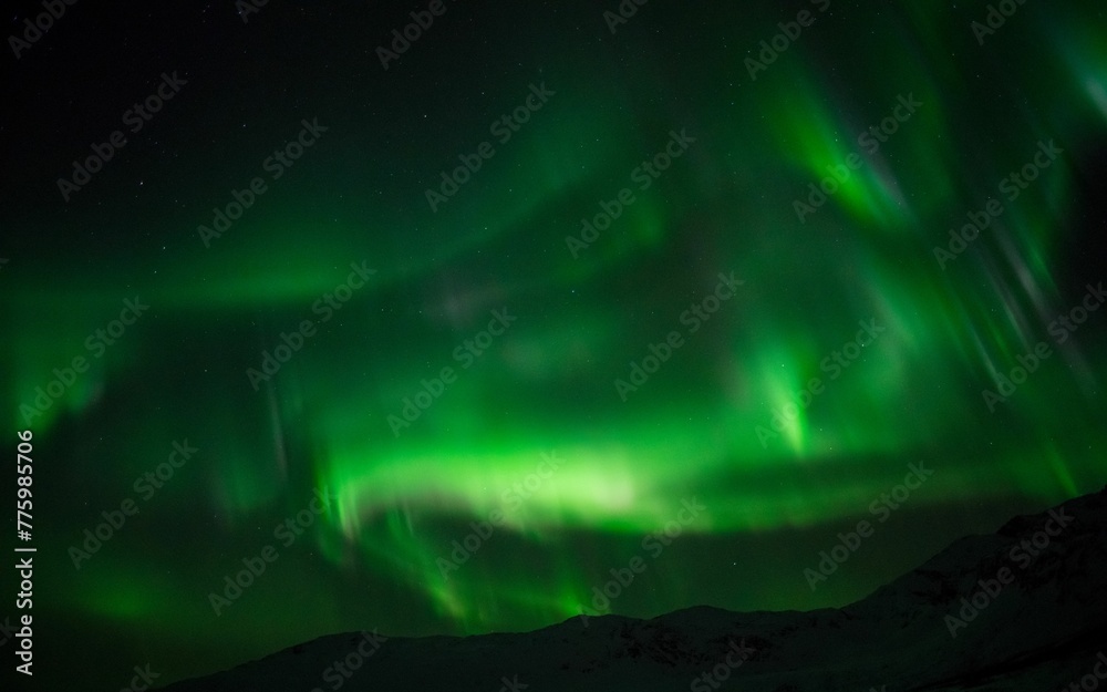 Beautiful shot of bright green aurora northern lights over mountains in Norway