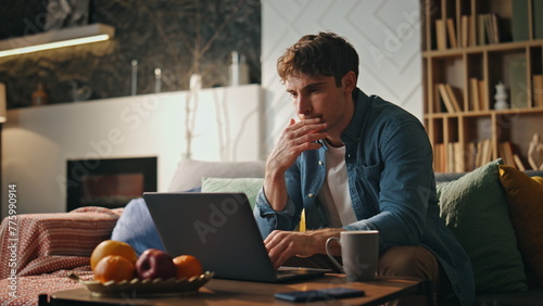 Busy programmer working laptop at home late evening. Freelancer surfing internet