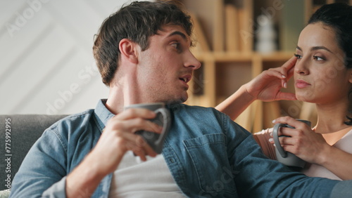 Romantic couple communicating home sitting cozy couch with coffee cup close up.