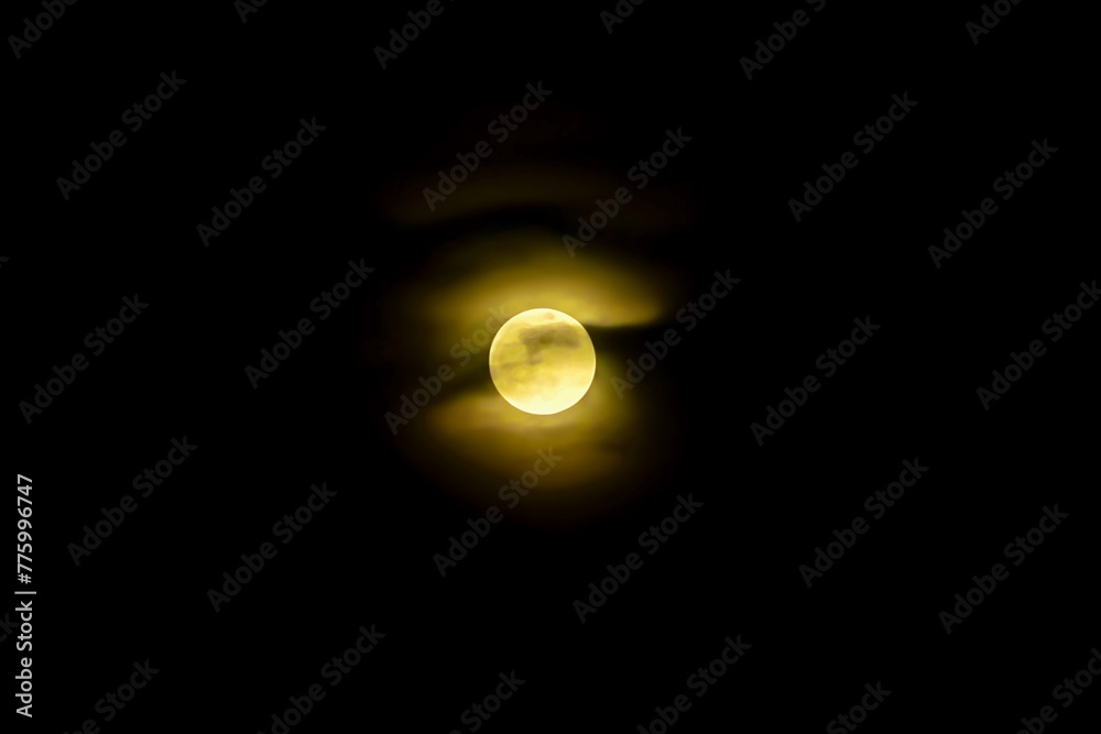 beautiful yellow full moon covered with clouds on the black night sky beautiful yellow full moon covered with clouds on the black night sky