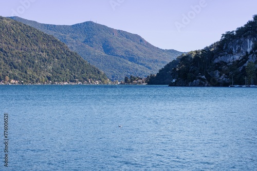 Scenic view of a blue lake surrounded by mountains covered with green forests on a sunny day © Wirestock