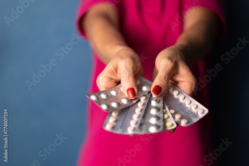 A woman holds several pill packs in her hands in a fan shape aga