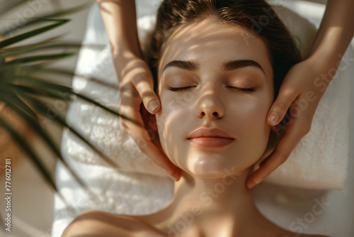 A beautiful woman is lying on her back in the spa, with both hands holding behind her head and being massaged in the style of a professional massage therapist. photo
