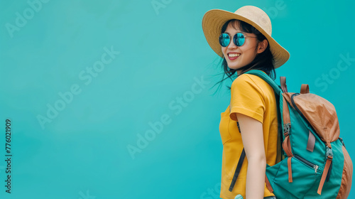 Amidst the tranquility of a blue background, a radiant young Asian tourist woman beams with excitement in blue set