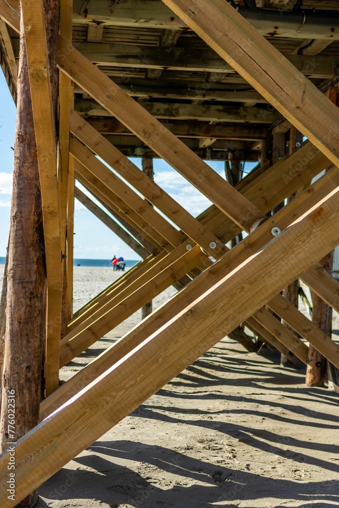 Vertical of the wooden jetty poles on the sandy beach of the North Sea in St. Peter-Ording Vertical of the wooden jetty poles on the sandy beach of the North Sea in St. Peter-Ording