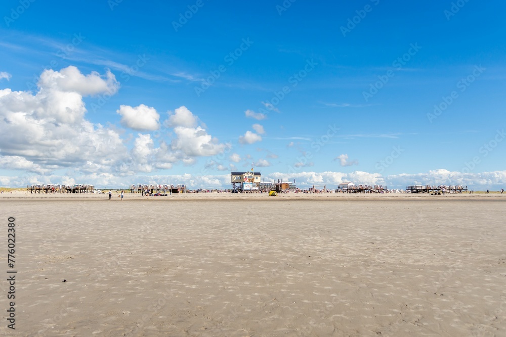 Old wooden jetty on the sandy beach of the North Sea in St. Peter-Ording against the blue sky