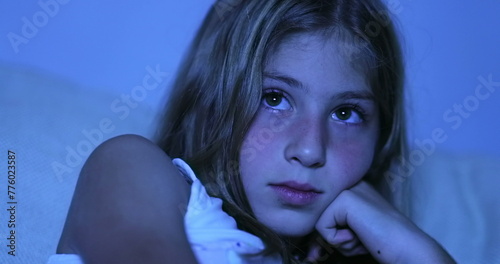 Child hypnotized by TV screen, little girl watching movie in the dark