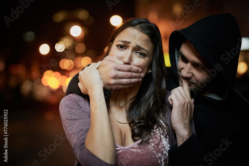 Woman, criminal and hand on mouth with fear for violence, danger and robbery in city at night with bokeh. People, portrait and silence emoji with terror, crime and stalker for kidnapping and hostage
