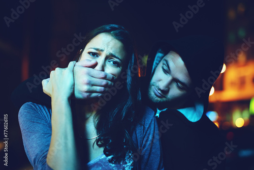 Woman, criminal and hand on mouth with terror for violence, danger and robbery in city at night with bokeh. People, portrait and silence emoji with fear, crime and gangster for kidnapping and hostage photo